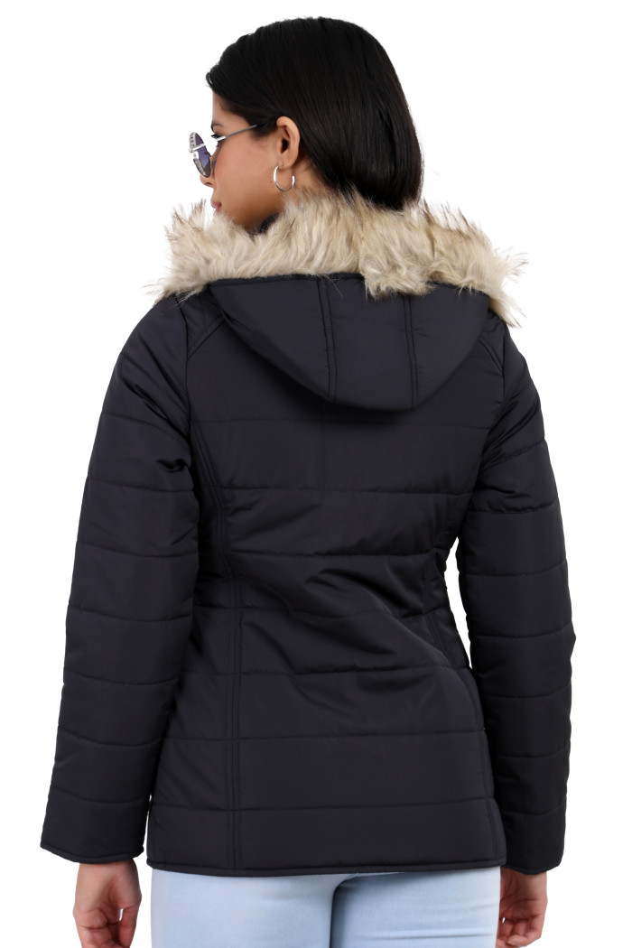 A back pose of a standing woman wearing black shades, Trufit’s dark grey matte quilted jacket with a detachable hood and blue jeans.